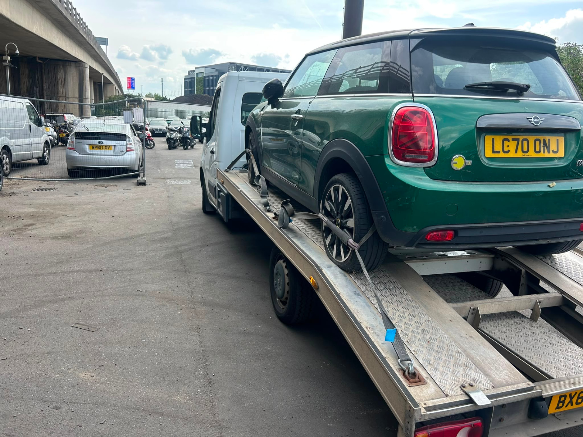 Green Mini Cooper loaded onto a recovery truck